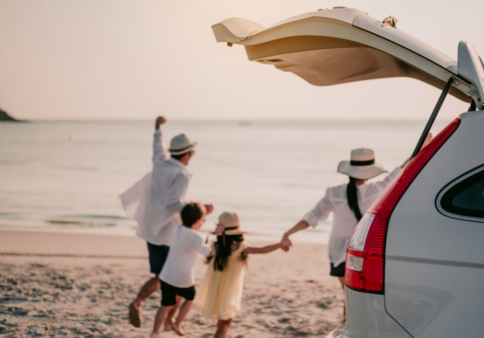 Asian family vacation holiday, Happy family running on the beach in the sunset.Happy family is running into the sea.Back view of a happy family on a tropical beach and a car on the side.