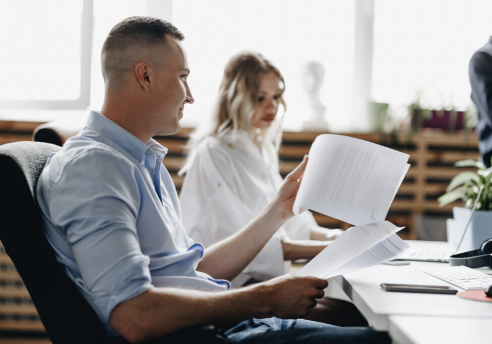 Beautiful woman and guy dressed in office style clothes are working sitting at desks in the light modern office equipped with modern office equipment .