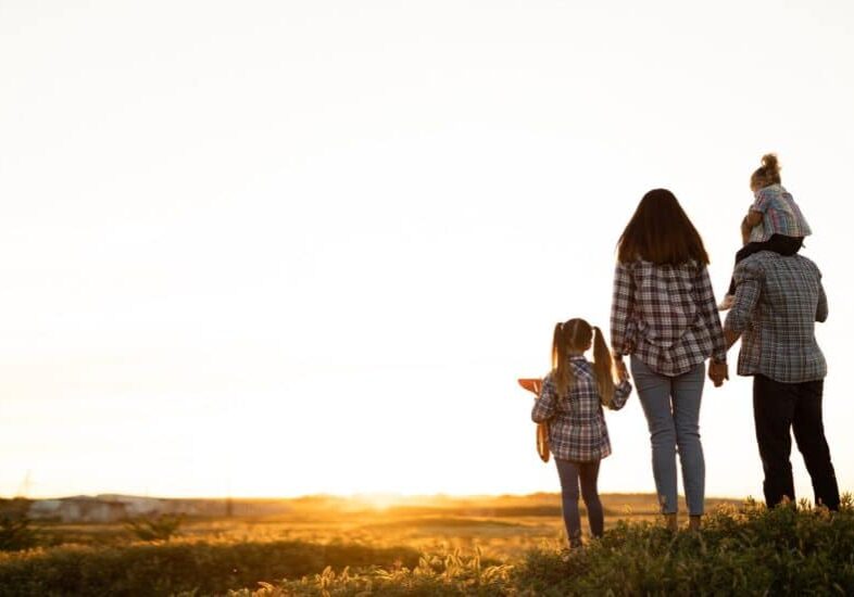 happy family dad mom and daughters walking on the field stand admiring the sunset looking at the sky and the sun. Healthy lifestyle for children and parents. family relationships.