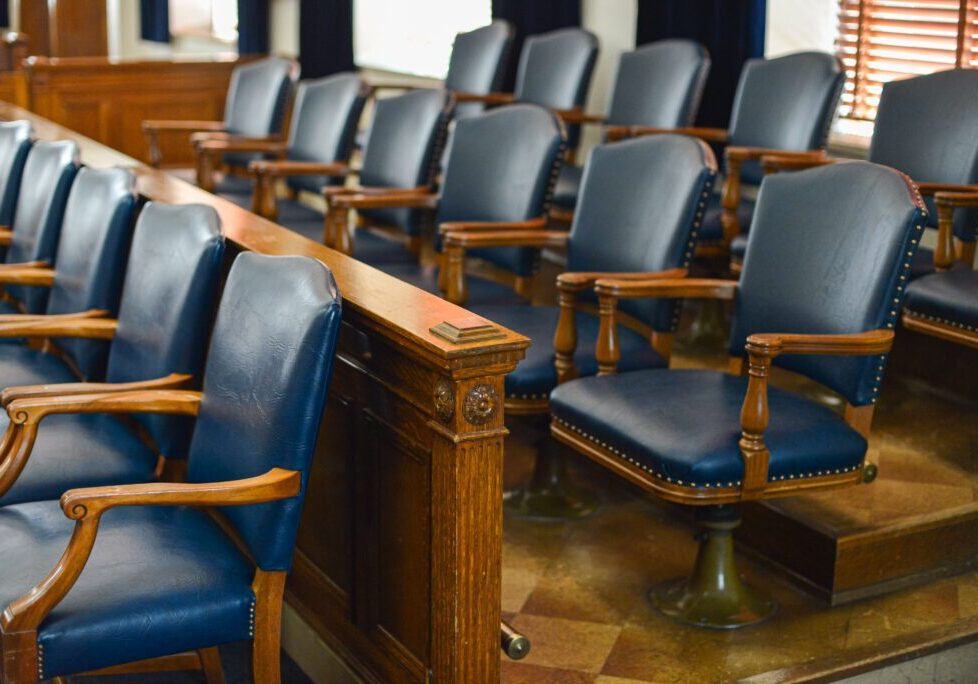 Empty jury box with blue leather chairs and windows in the background An empty jury box with blue leather chairs and windows in the background