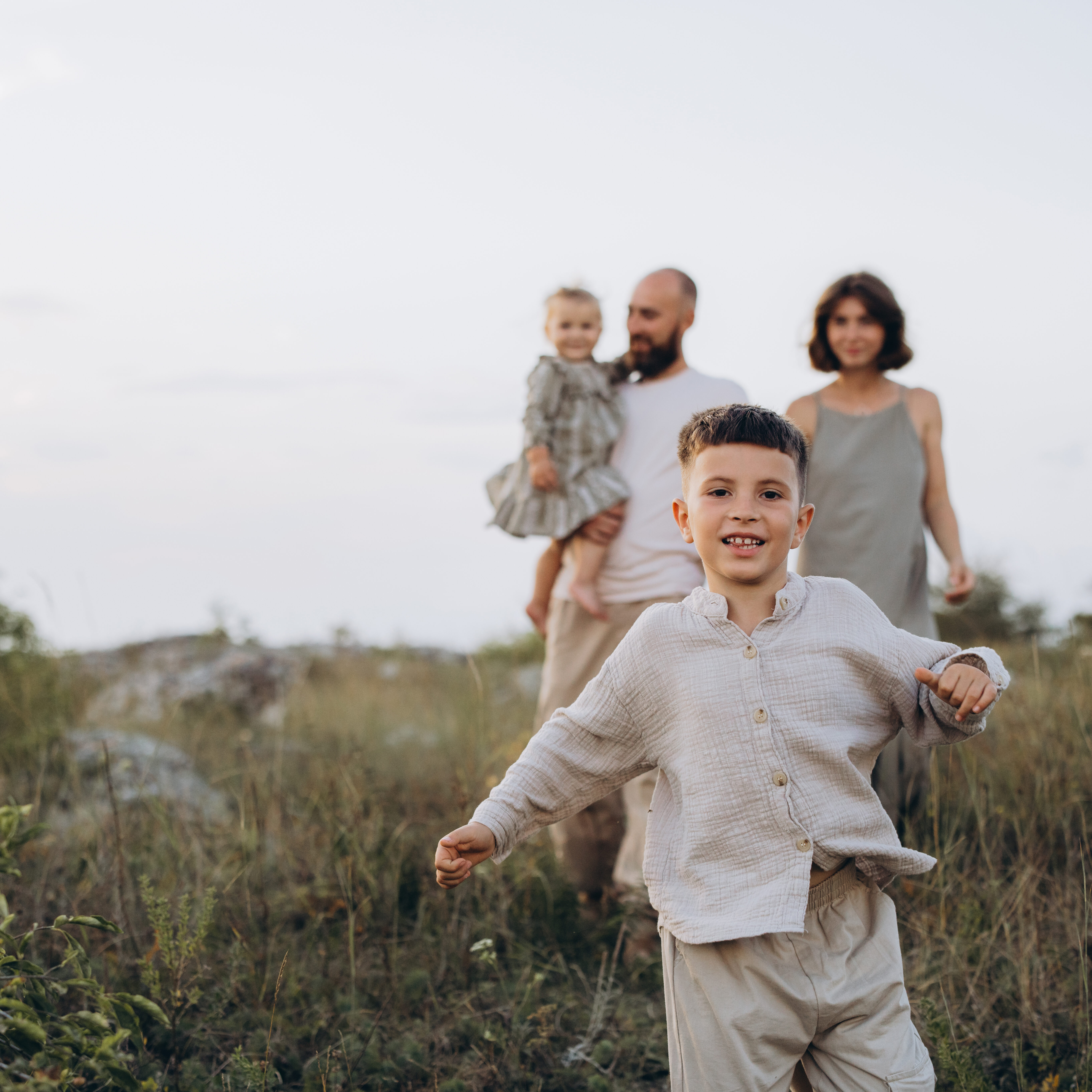 Happy Family Enjoying a Walk in Nature on a Sunny Day A cheerful family of four, including parents and children, enjoying a walk outdoors in nature during a sunny day, capturing moments of joy and togetherness.