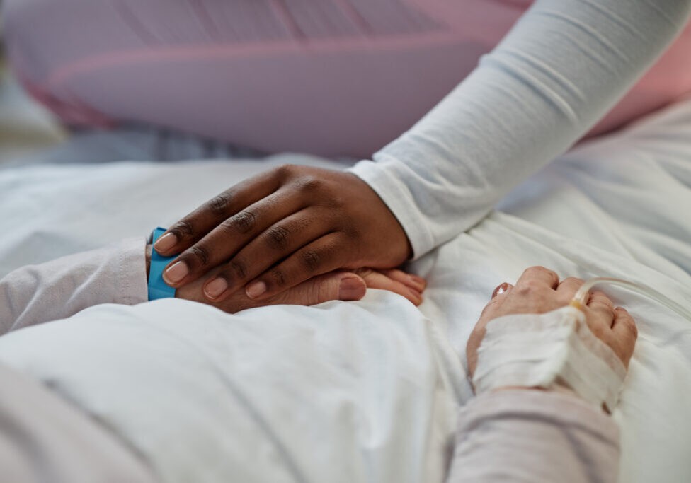 Compassionate touch between patient's hands in hospital setting. Gentle holding gesture providing comfort and emotional support during recovery