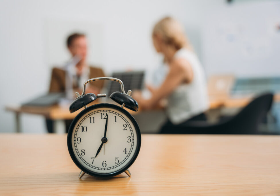 Workplace with alarm clock in modern style on background business meeting Workplace with alarm clock in modern style on background business meeting